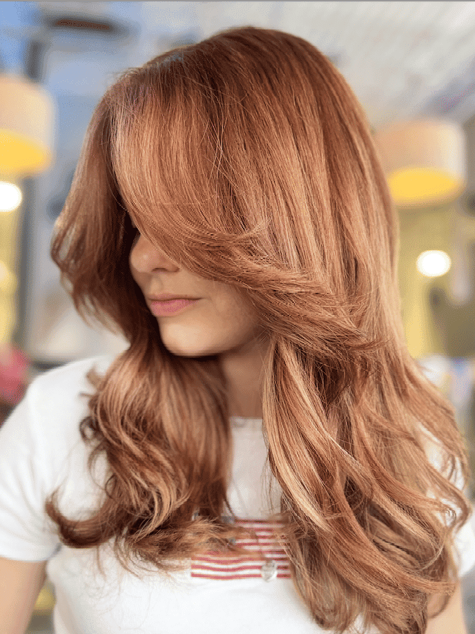 Woman with long, wavy auburn hair in a salon setting.